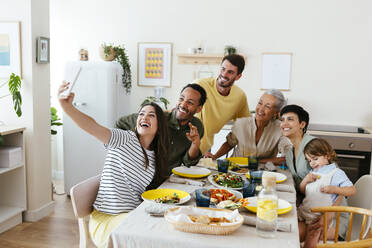 Eine glückliche Familie hält einen Moment zusammen fest, während sie am Esstisch in ihrer Küche sitzt - EBSF03691