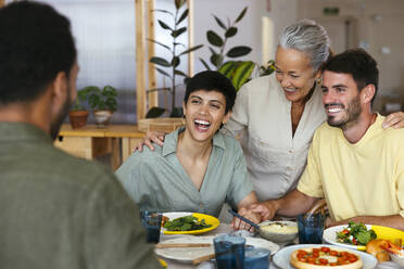 Happy family having lunch together at dining table in kitchen - EBSF03696