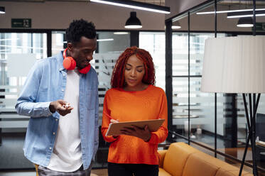 Business colleagues discussing over clipboard at workplace - PGF01529