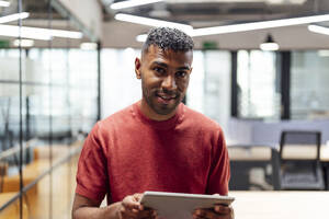 Smiling businessman with tablet PC at office - PGF01539