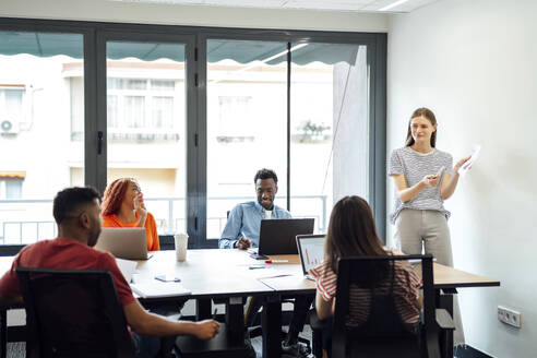 Young businesswoman having discussion over document with colleagues - PGF01580