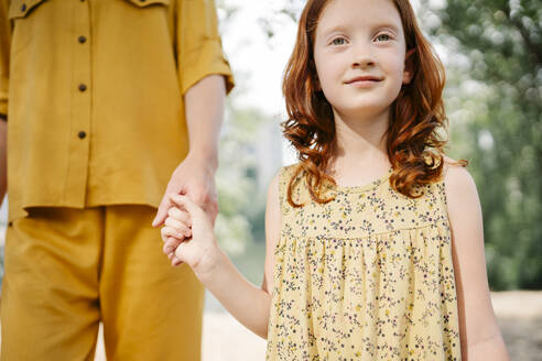 Smiling daughter holding mother's hand in park - SSYF00181