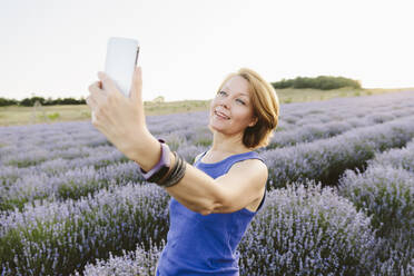 Smiling woman taking selfie amidst lavender field - SIF00751