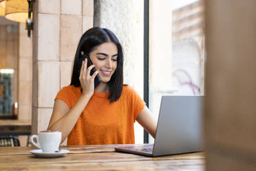 Freelancer talking on smart phone in cafe - LMCF00467