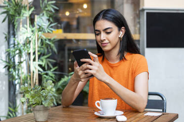Junge Frau benutzt Smartphone in einem Cafe - LMCF00481