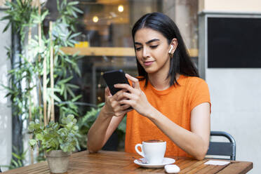 Young woman using smart phone at cafe - LMCF00481