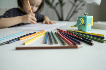 Boy drawing with colored pencils on table at home - ANAF01849