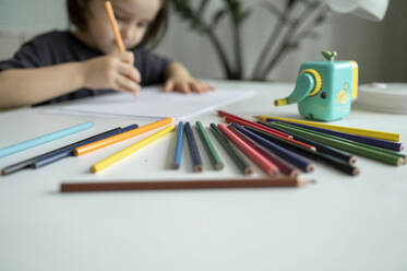 Junge zeichnet mit Buntstiften auf dem Tisch zu Hause - ANAF01849