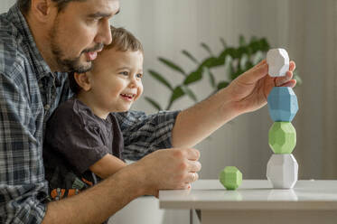 Father and son building tower of blocks at home - ANAF01853