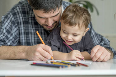 Father and son coloring together at home - ANAF01854