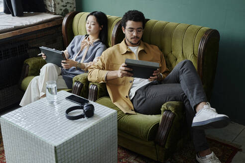 Geschäftsleute, die entspannt in Sesseln sitzen und einen Tablet-PC benutzen - DSHF00907