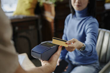 Frau zahlt mit Kreditkarte am Automaten in einem Cafe - DSHF00922