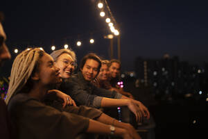 Lächelnde Freunde verbringen nachts ihre Freizeit auf dem Dach - IKF01025