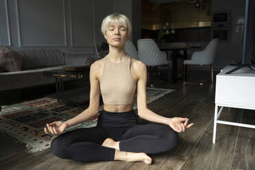 Blonde Frau meditiert zu Hause auf dem Boden - YBF00026