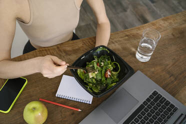 Ernährungsberaterin isst Salat am Esstisch - YBF00042