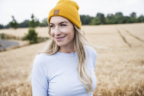 Smiling woman wearing knit hat at field - UUF29655