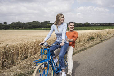 Glückliche Frau, die eine Fahrradtour mit einem Mann genießt - UUF29694