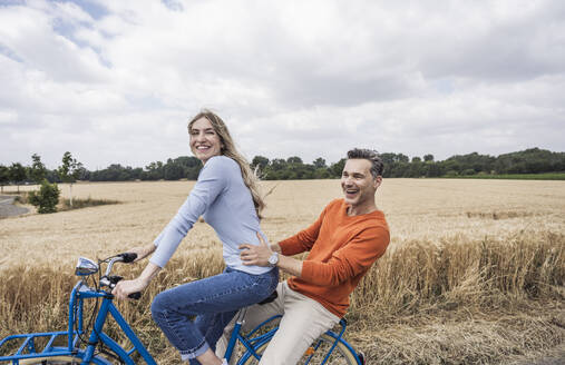 Happy man enjoying bicycle ride with woman - UUF29696