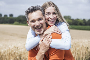 Glückliche Frau umarmt Mann vor einem Feld - UUF29702