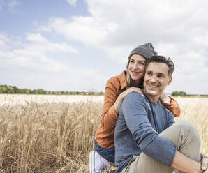 Contemplative couple sitting at field - UUF29743