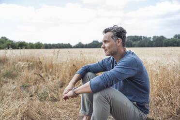 Thoughtful mature man sitting in field - UUF29770