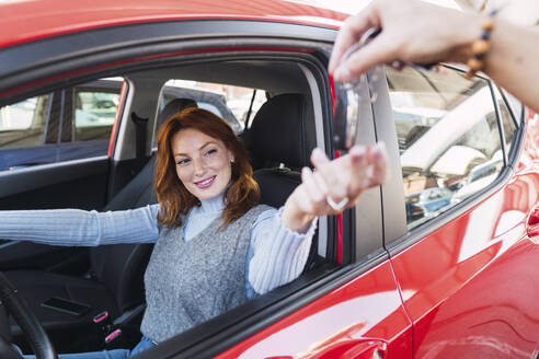 Lächelnde Frau nimmt Autoschlüssel von Mann - PNAF05882