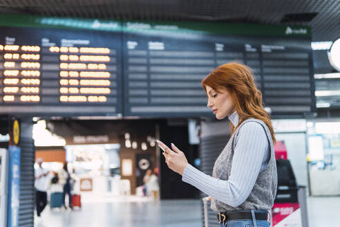 Frau benutzt Smartphone am Flughafen - PNAF05887