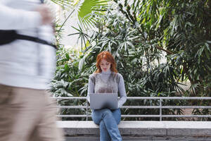 Geschäftsfrau arbeitet am Laptop vor Pflanzen - PNAF05902