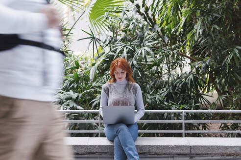 Geschäftsfrau arbeitet am Laptop vor Pflanzen - PNAF05902