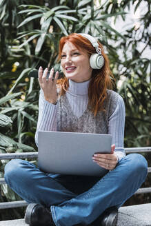 Happy businesswoman talking on mobile phone in front of plants - PNAF05932