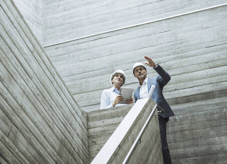Businessman gesturing and having discussion with colleague on staircase - UUF29795