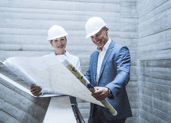 Glückliche Architekten bei der Arbeit und Planung mit dem Bauplan vor Ort - UUF29803