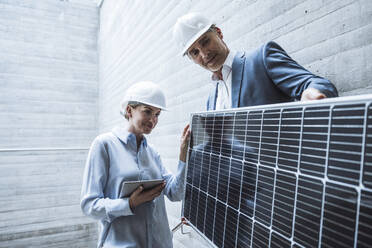 Lächelnde Ingenieure diskutieren auf der Baustelle über Solarmodule - UUF29811