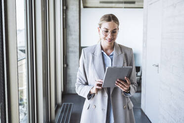 Lächelnde Geschäftsfrau mit Tablet-PC im Büroflur - UUF29831