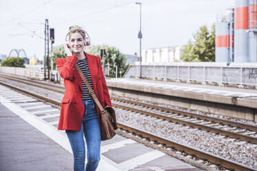 Smiling woman listening to music through wireless headphones - UUF29891