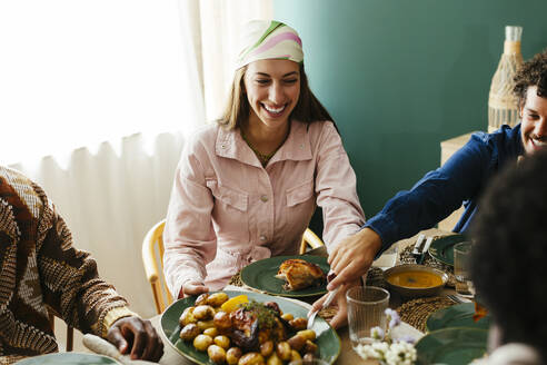 Lächelnde Freunde beim Thanksgiving-Mittagessen am Esstisch - EBSF03702