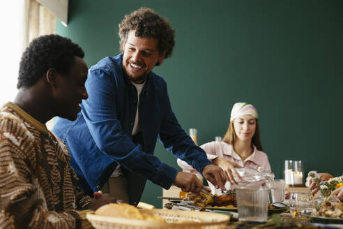 Friends having thanksgiving lunch at dining table - EBSF03703