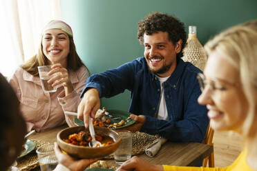 Happy friends enjoying thanksgiving lunch at dining table - EBSF03707