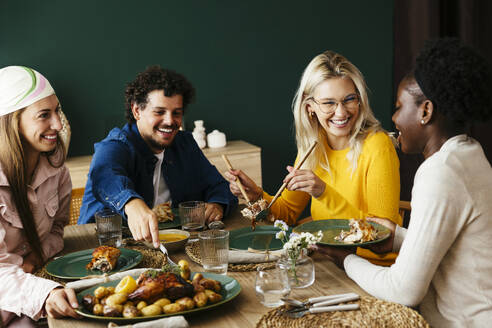 Happy friends enjoying thanksgiving lunch at home - EBSF03721