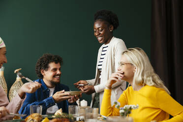 Smiling friends having conversation at dining table - EBSF03723