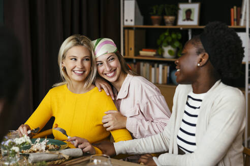 Lächelnde Freunde beim Thanksgiving-Mittagessen am Esstisch in einem Haus - EBSF03728