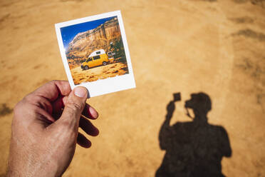 From above of crop anonymous person holding instant picture of scenic camper van by hilly canyon in daylight at Rojo Teruel Spain - ADSF46057