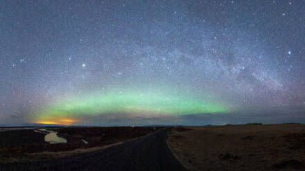 From below colorful green polar lights shining on sky over calm river with rocky formation in wild nature at night time in Iceland - ADSF46110