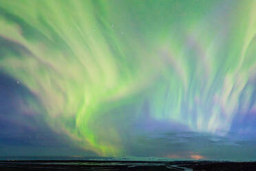 From below colorful green polar lights shining on sky over calm river with rocky formation in wild nature at night time in Iceland - ADSF46111