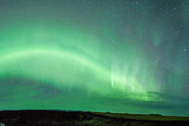 From below colorful green polar lights shining on sky over field with rocky formation in wild nature at night time in Iceland - ADSF46112