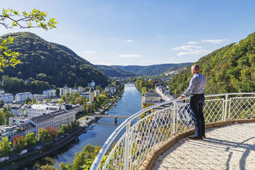 Deutschland, Rheinland-Pfalz, Bad Ems, Mann steht auf einer Terrasse mit Blick auf die Kurstadt an der Lahn - GWF07887