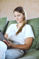 Smiling freelancer using tablet PC on sofa at home - YHF00024