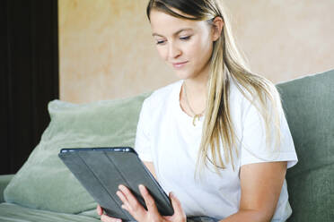 Smiling businesswoman using tablet PC on sofa - YHF00026