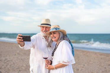 Älteres Paar genießt den Strand und hält Erinnerungen mit einem Selfie auf ihrem Smartphone fest - ADSF46160