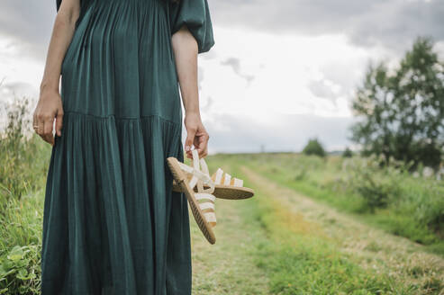 Stehende Frau mit Schuhen in einem Feld - ANAF01887